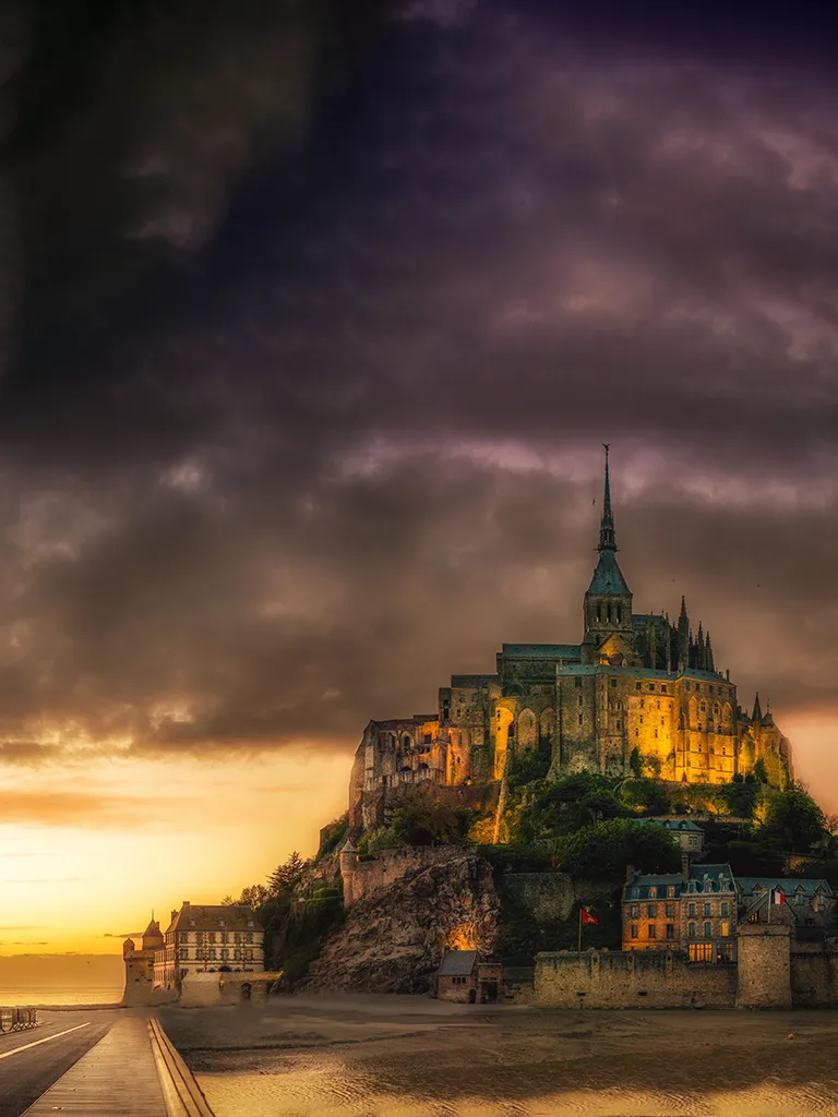 Mont Saint Michel à la tombée de la nuit sous une golden hour avant un orage